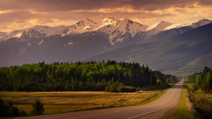 Road leading to snow-capped mountains at sunset