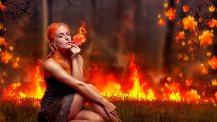 Woman with fiery leaf in burning forest