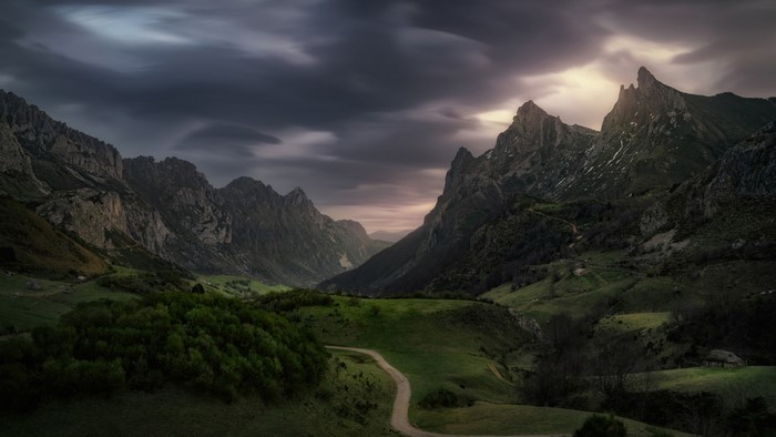 Mountain valley with dramatic clouds and a winding path