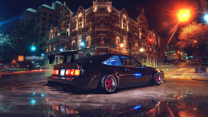Modified black Toyota Supra with large spoiler at night