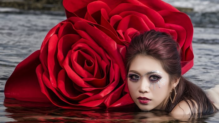Woman with large red rose in water