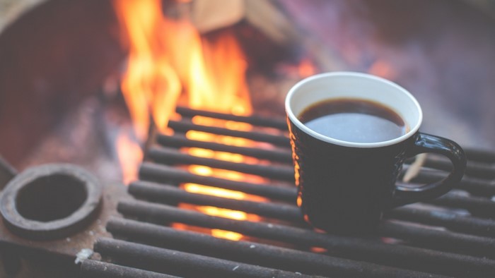 Coffee cup on a grill with a campfire