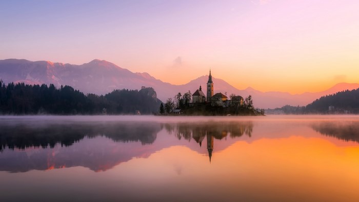 Island church and castle on a misty lake at sunrise