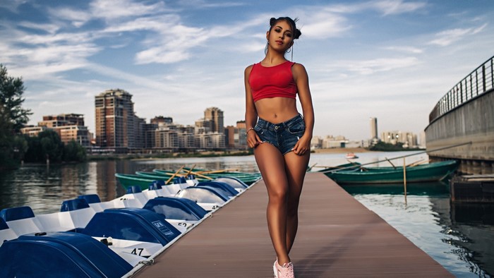 Girl in red top and denim shorts on a pier