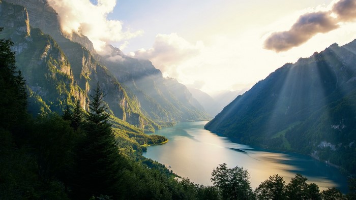 Sunlight beams over a mountain lake and valley