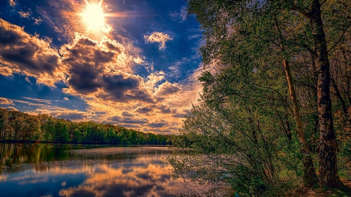 Lake and forest with sun and clouds