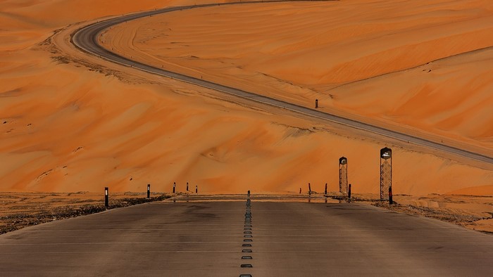 Desert road with sand dunes and lights