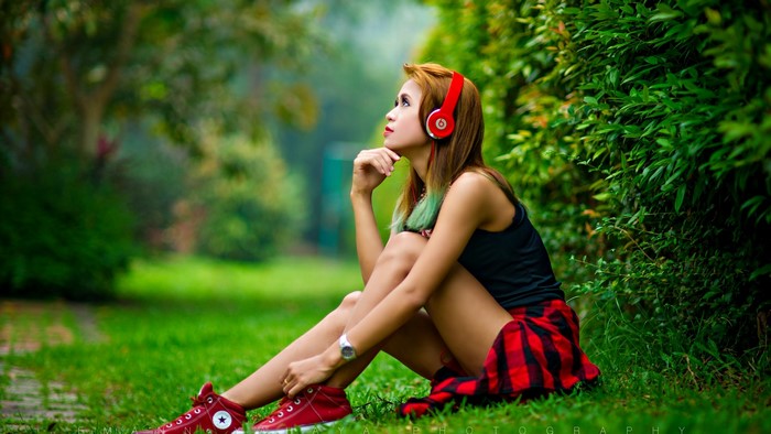 Girl with headphones sitting in a park