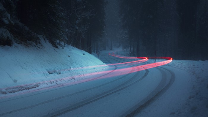 Light trails on a snowy forest road at night