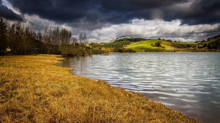 Lake with rolling hills and dark clouds