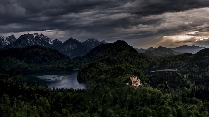Castle on a hill overlooking a lake and mountains