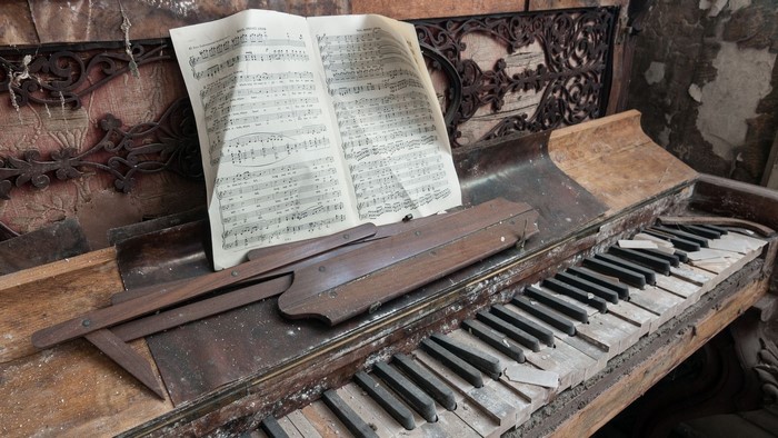 Old broken piano with sheet music