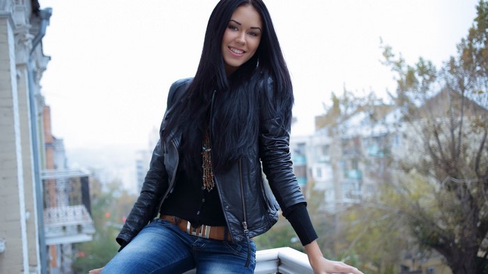 Young woman in leather jacket and jeans on balcony