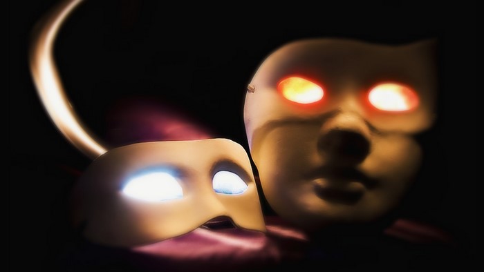 Two masks with glowing eyes in the dark