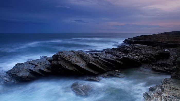 Rocky coast with ocean waves at dusk