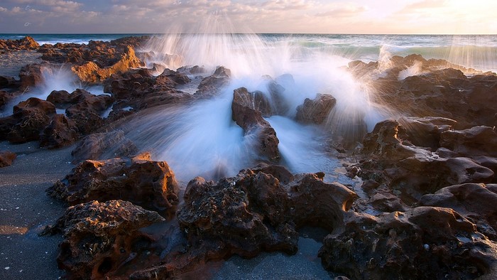 Waves crashing on rocky shore at sunset