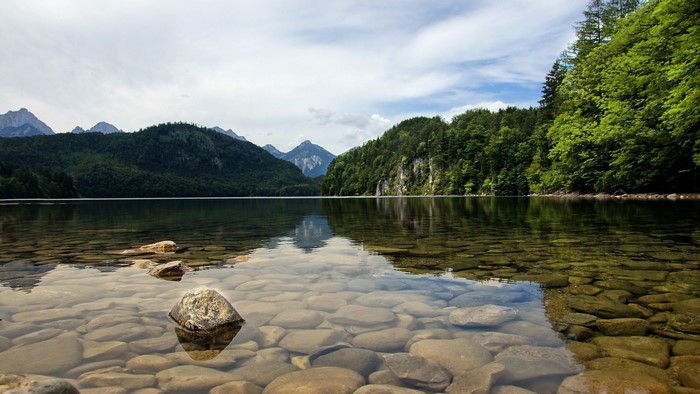 Clear lake with rocky bottom and forested mountains
