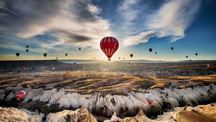 Hot air balloons over a rocky landscape at sunrise