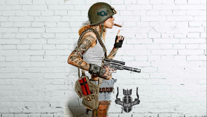 Tattooed woman in military gear holding a gun