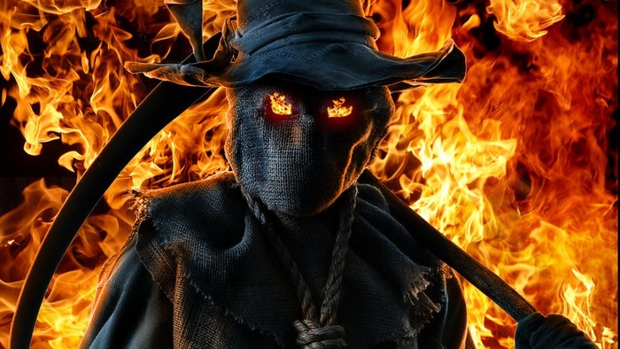 Scarecrow with scythe in front of fire