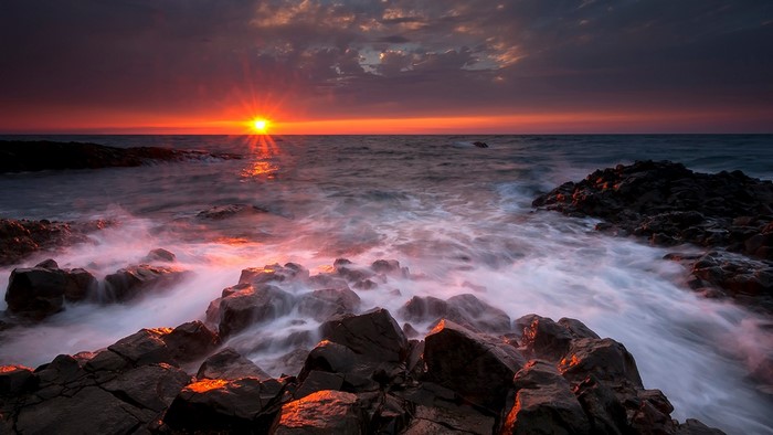 Sunset over rocky shore with waves