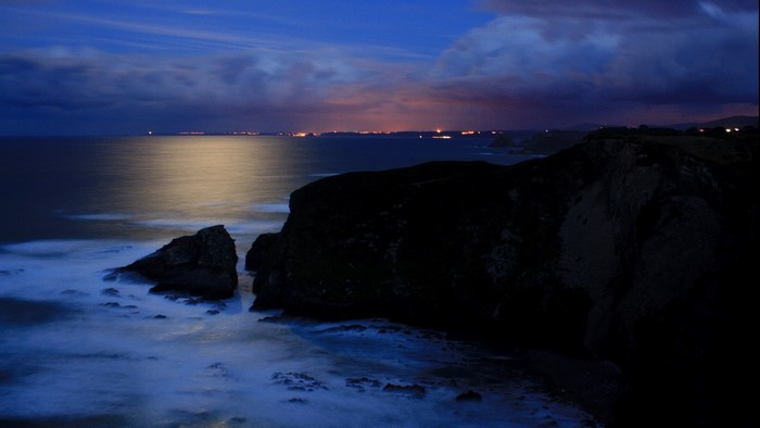 Nighttime ocean view with distant city lights