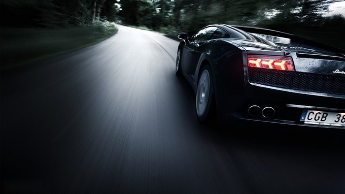 Black Lamborghini driving on a road