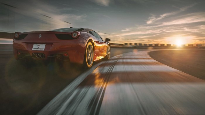 Red Ferrari 458 Italia on a race track at sunset