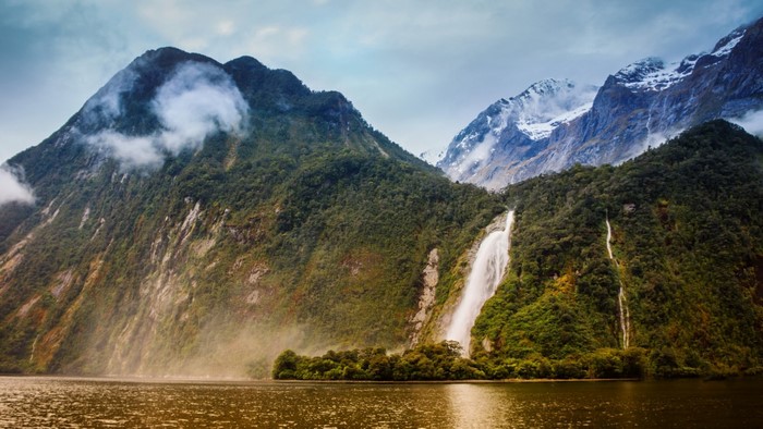 Waterfalls cascading down lush green mountains into a lake