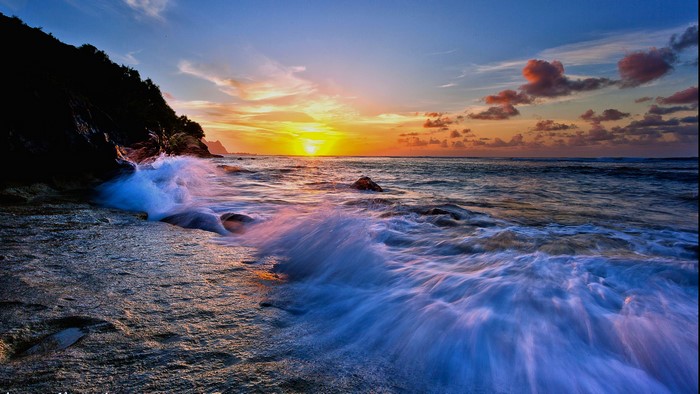 Waves crashing on rocky shore at sunset