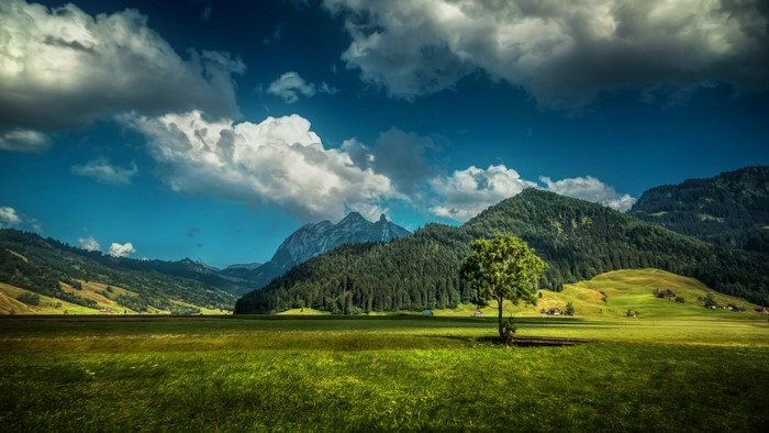 Green valley with mountains and clouds