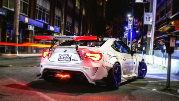 White modified sports car with a large rear spoiler at night