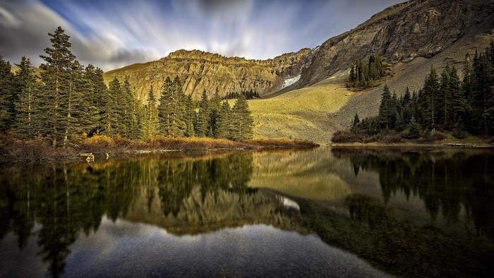 Mountain lake reflection with pine trees and rocky slopes