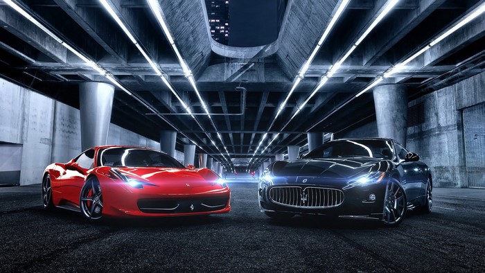 Red Ferrari and black Maserati under bridge