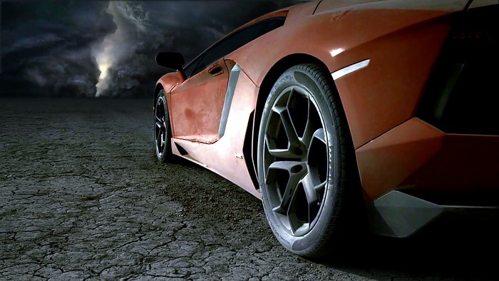 Orange sports car on cracked ground with storm in background