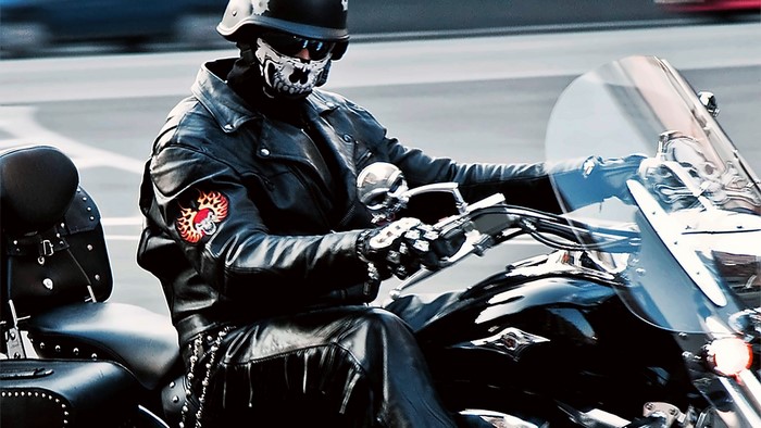 Biker wearing skull mask and leather riding a motorcycle