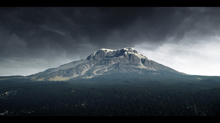 Snow-capped mountain range above a dark forest under stormy skies