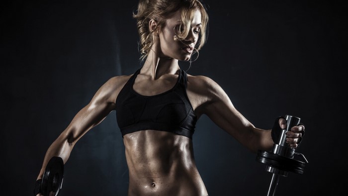 Woman with toned abs holding weights
