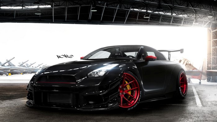 Black Nissan GT-R with red wheels in hangar