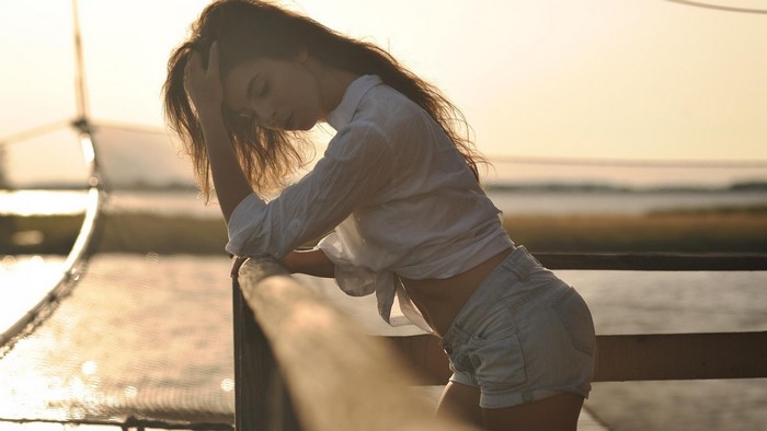 Woman in white shirt and denim shorts leaning on railing