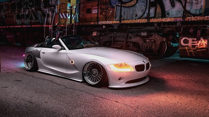 White BMW Z4 convertible parked next to graffiti-covered train