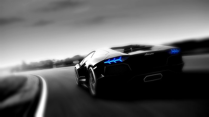 Black Lamborghini Aventador driving on a road