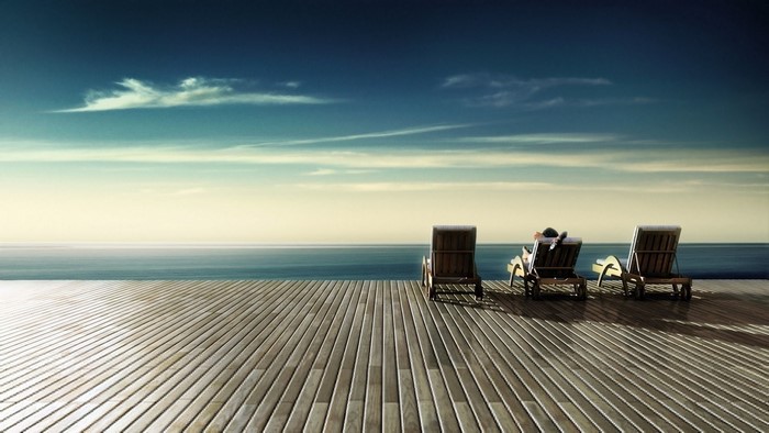 People relaxing on lounge chairs by the ocean