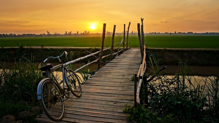 Bicycle on a wooden bridge at sunset