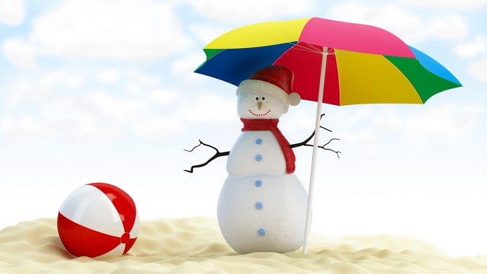 Snowman with umbrella and beach ball on sand