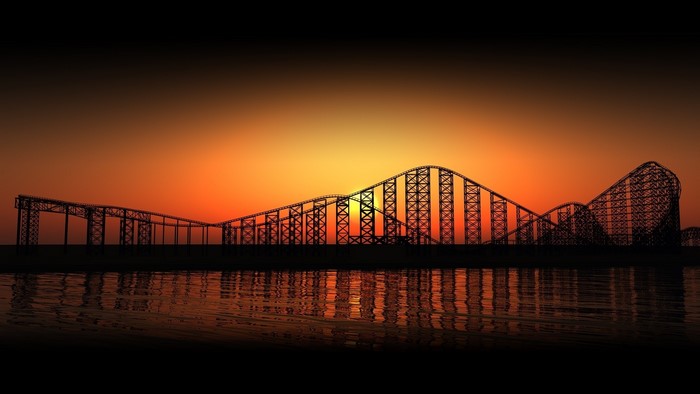 Roller coaster silhouette at sunset over water