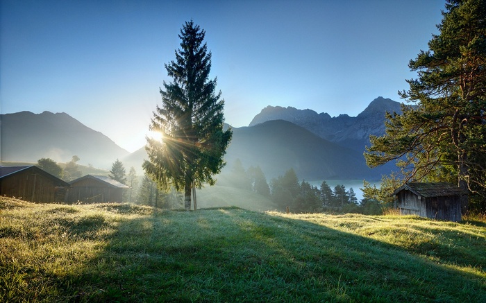 Sunrise over a mountain valley with cabins and a lake