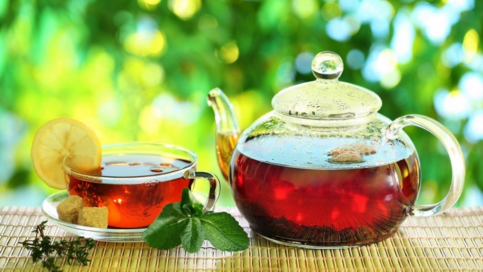 Glass teapot and cup of lemon tea with sugar cubes