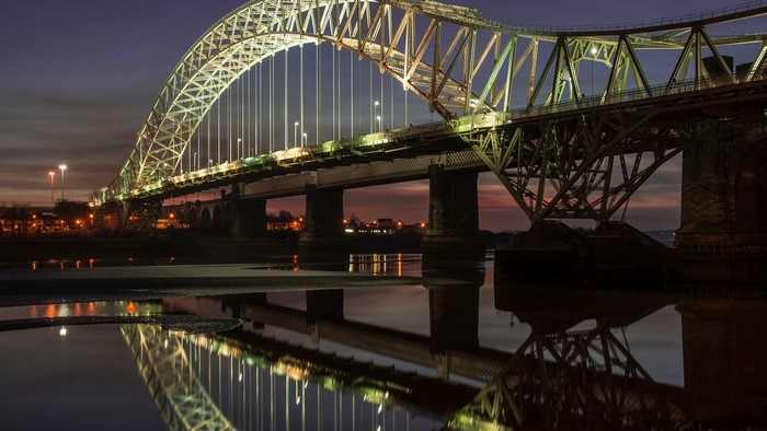 Steel bridge illuminated at night with reflections