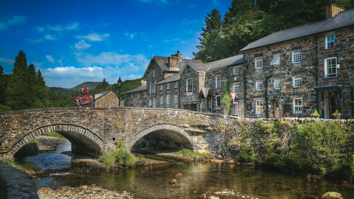 Stone bridge over a river with stone buildings in Wales
